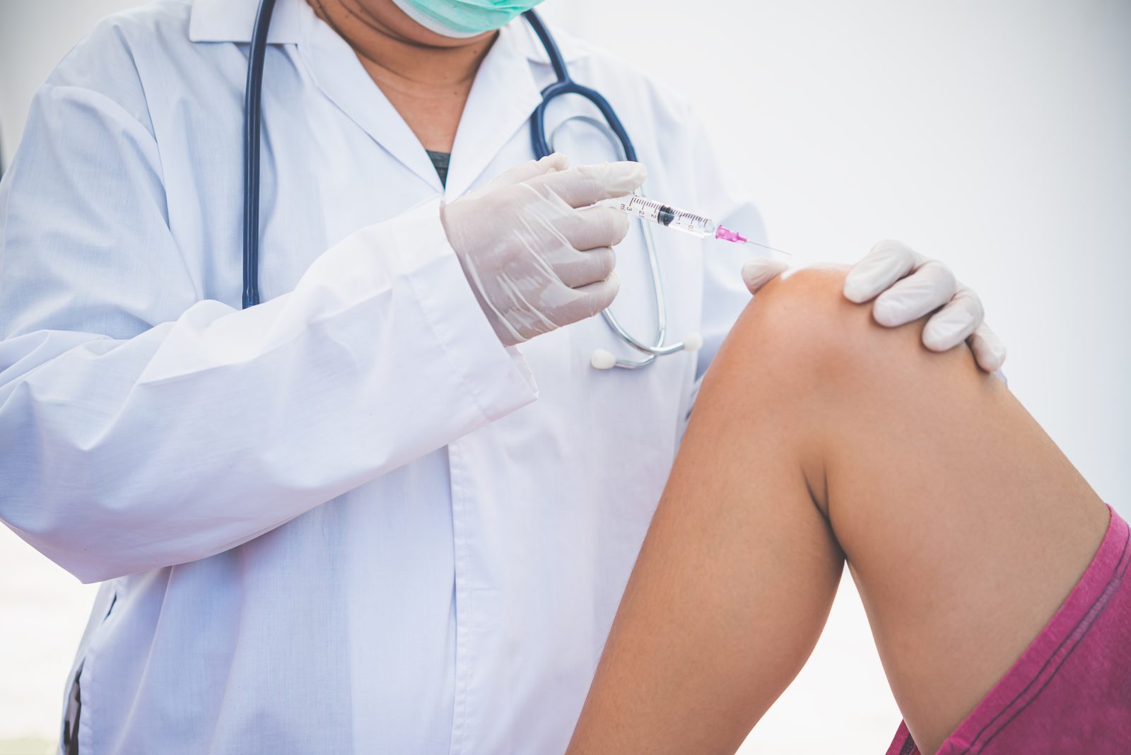 Clinician administering an intra-articular injection into a patient knee